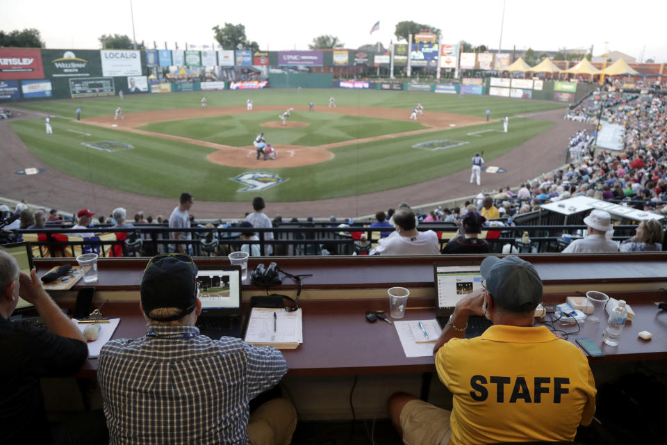 Ron Besaw, right, operates a laptop computer as home plate umpire Brian deBrauwere, gets signals from radar with the ball and strikes calls during the fourth inning of the Atlantic League All-Star minor league baseball game, Wednesday, July 10, 2019, in York, Pa. deBrauwere wore an earpiece connected to an iPhone in his ball bag which relayed ball and strike calls upon receiving it from a TrackMan computer system that uses Doppler radar. The independent Atlantic League became the first American professional baseball league to let the computer call balls and strikes during the all star game. (AP Photo/Julio Cortez)