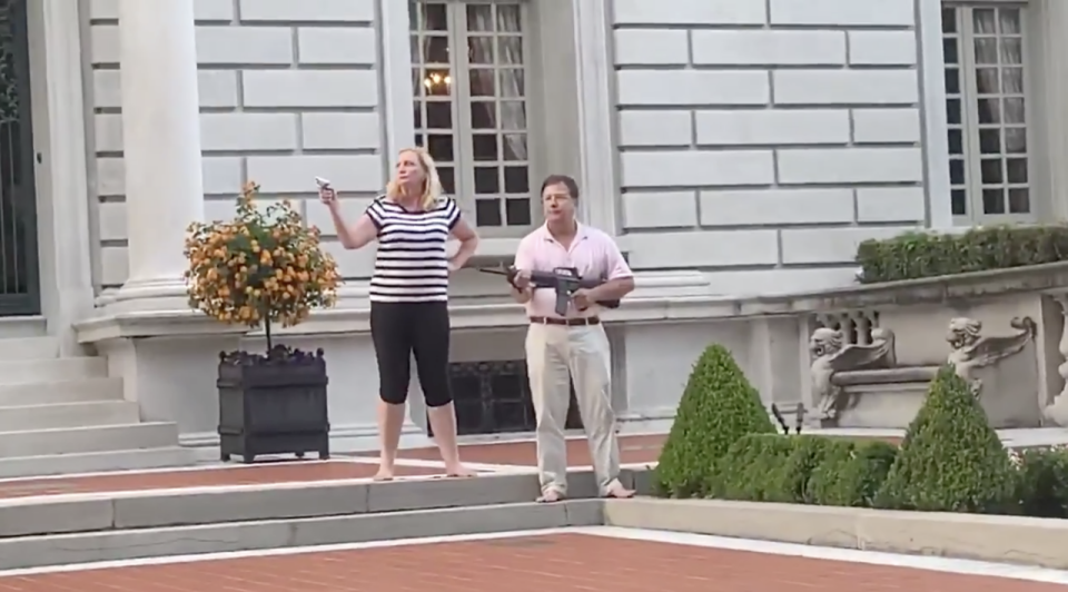 Pictured is Mark and Patricia McCloskey outside their home holding guns as Black Lives Matter protesters walk past their home. Source: Twitter