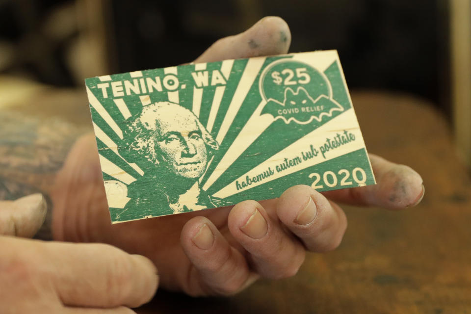 In this May 21, 2020, Loren Ackerman holds a piece of wooden money he printed on an 1890s-era press in Tenino, Wash. In an effort to help residents and local merchants alike get through the economic fallout of the coronavirus pandemic, the small town has issued wooden currency for residents to spend at local businesses, decades after it created a similar program during the Great Depression. (AP Photo/Ted S. Warren)