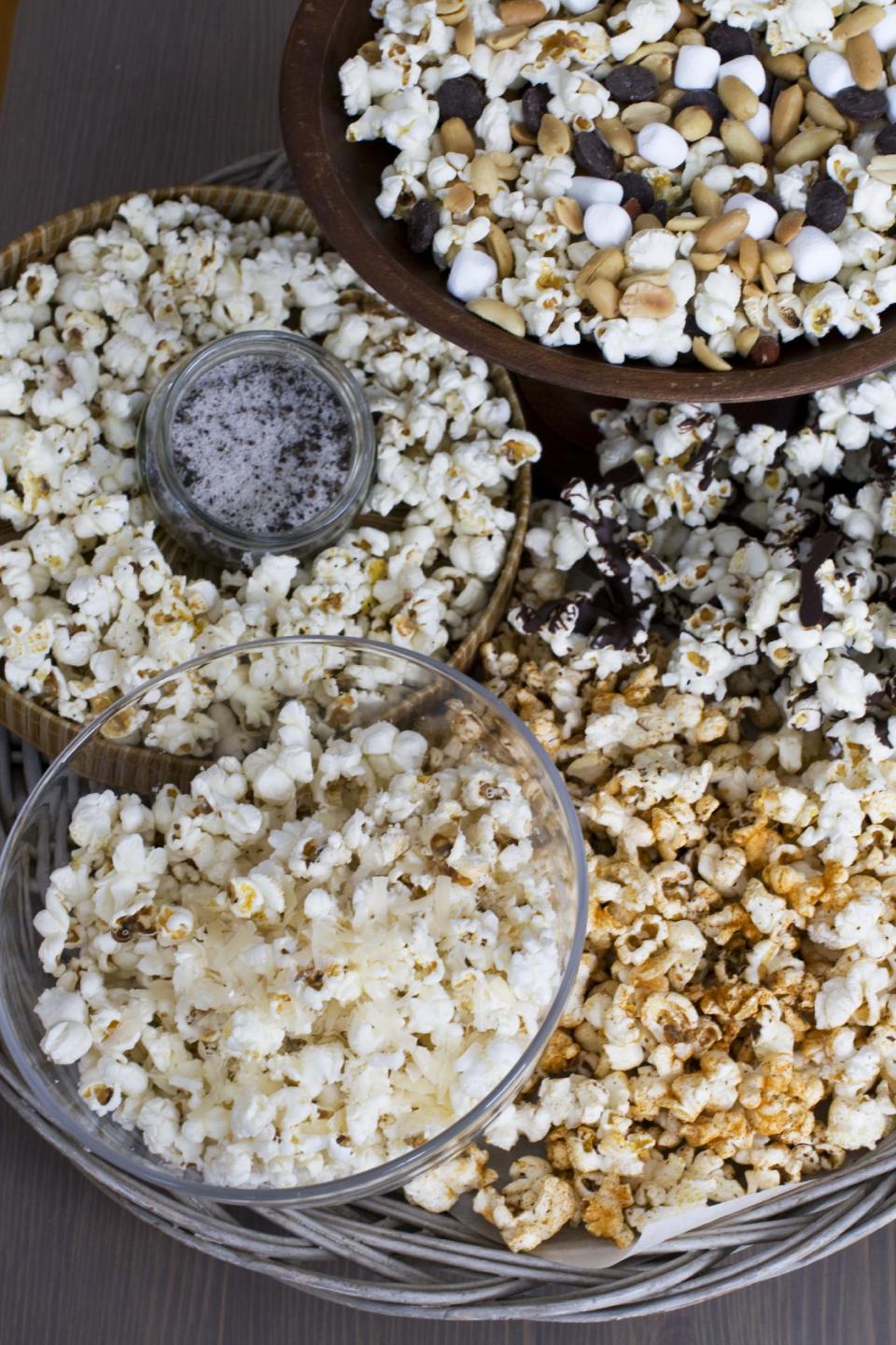 In this image taken on Jan. 28, 2013, the recipe for Stovetop Popcorn Many Ways, from top clockwise, mini marshmallows, chocolate chips and salted peanuts, melted chocolate, sweet and spicy barbeque rub, finely grated parmesan cheese, and truffle salt, is shown in Concord, N.H. (AP Photo/Matthew Mead)