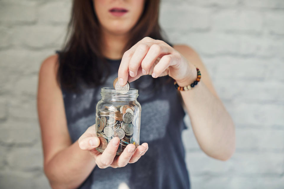 Young woman puts money in a glass