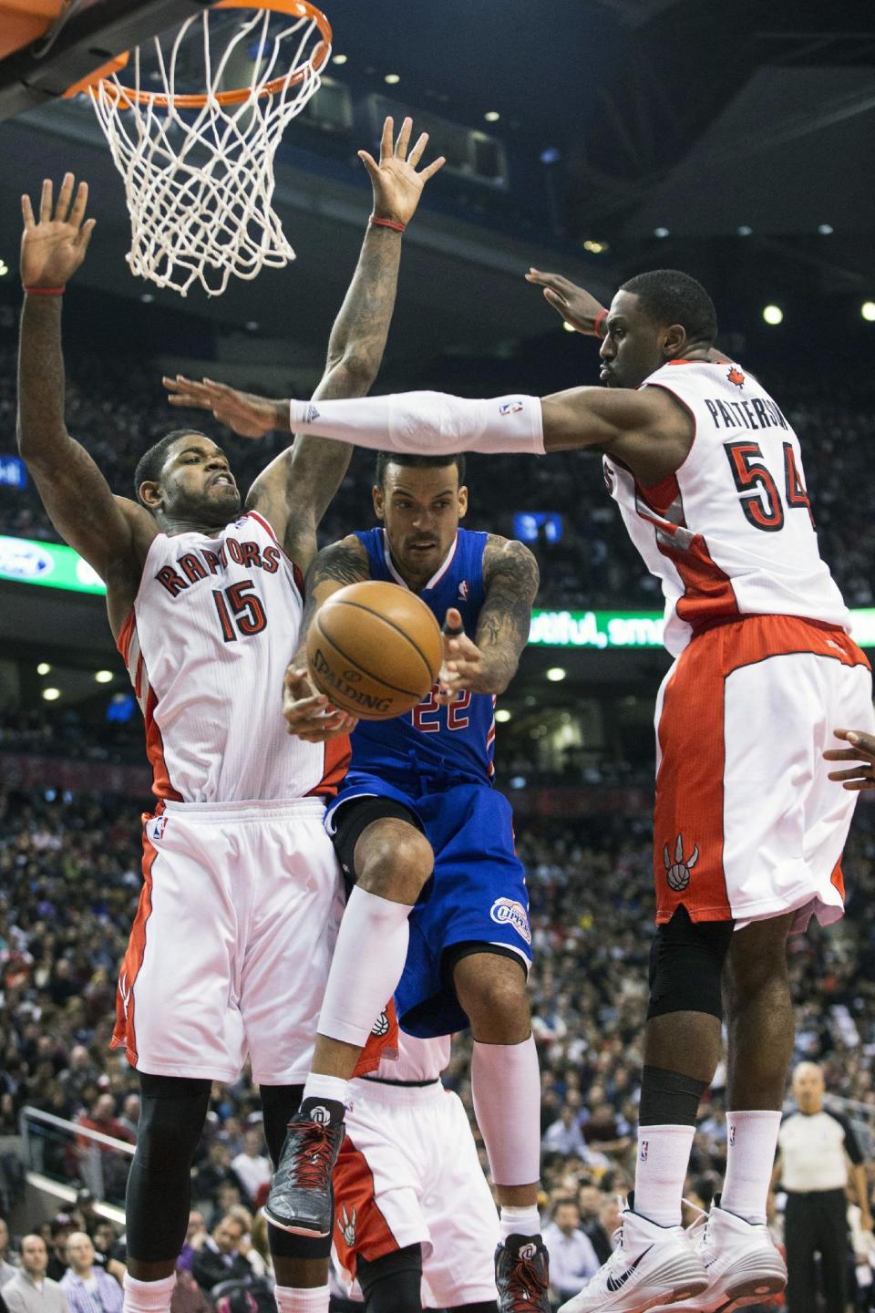Los Angeles Clippers' Matt Barns, center, looks to pass between Toronto Raptors' Amir Johnston, left, and Patrick Patterson during the first half of an NBA basketball game, Saturday, Jan. 25, 2014 in Toronto. (AP Photo/The Canadian Press, Chris Young)