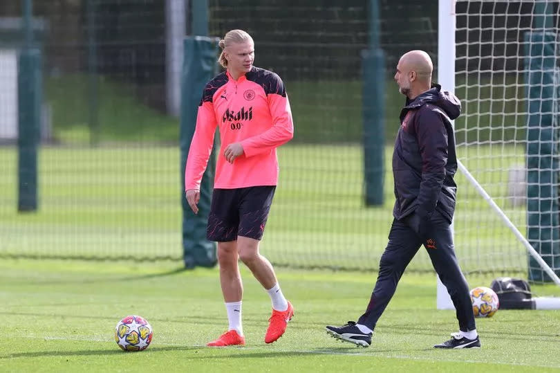 Manchester City manager Pep Guardiola speaks with Erling Haaland during training