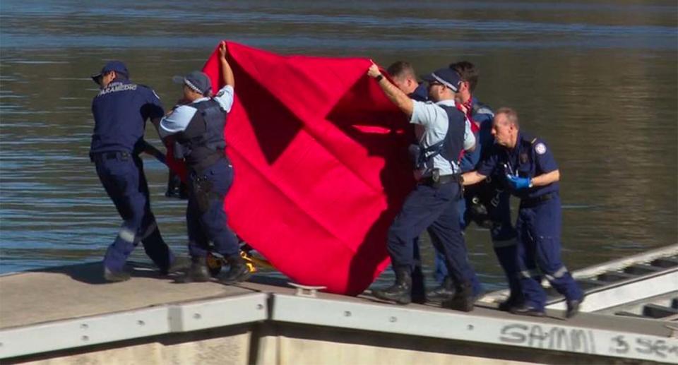 Police crews move a child to an ambulance after she fell into the Hawkesbury River from a boat. 
