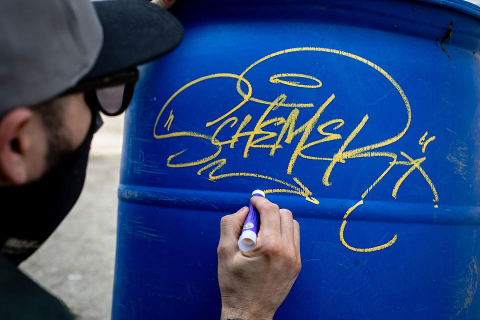 Los Angeles graffiti artist Skeam, who was among many who painted the abandoned Oceanwide Plaza towers in downtown L.A. Wearing a mask to remain anonymous, he demonstrates one of his tagging signatures on a barrel at a construction site. The unfinished glass towers -- the tallest is 55 stories -- became a worldwide sensation when they were covered by graffiti art.