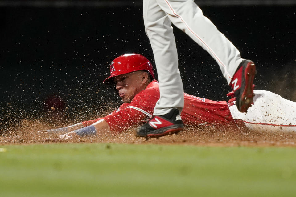 Los Angeles Angels' Ehire Adrianza, bottom, slides past Philadelphia Phillies relief pitcher Seranthony Dominguez to score on a wild pitch during the seventh inning of a baseball game, Monday, April 29, 2024, in Anaheim, Calif. Mike Trout also scored after a throwing error by Phillies catcher Garrett Stubbs. (AP Photo/Ryan Sun)