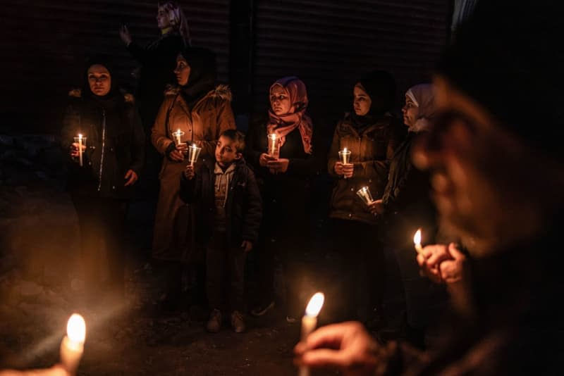 Civilians and members of the White Helmets light candles to commemorate the victims of the 6 February earthquake in front of a destroyed building in the city of Jindires. Tens of thousands of people lost their lives in Turkey and Syria on 6 February 2023. Anas Alkharboutli/dpa