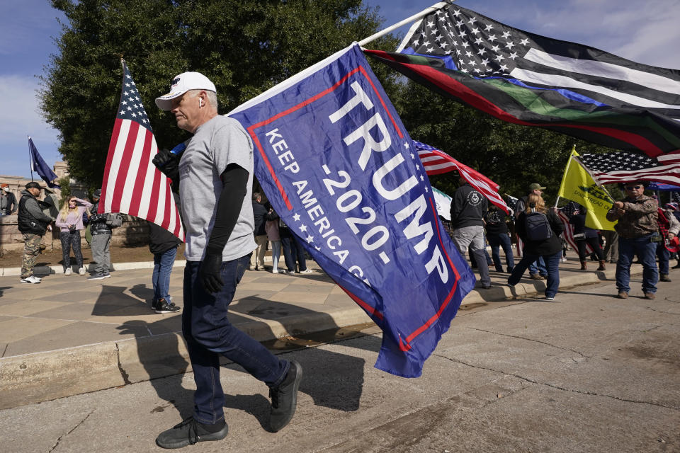 A supporter of President Donald Trump walks with flags near the Texas State Capitol during a rally, Saturday, Jan. 9, 2021, in Austin, Texas. (AP Photo/Eric Gay)