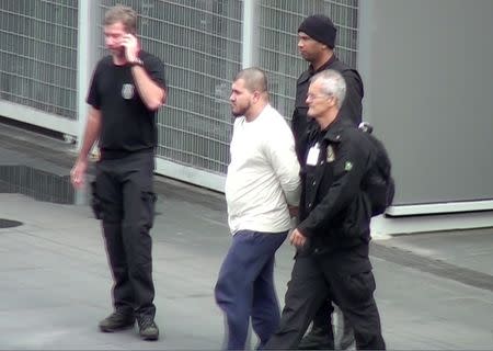 Brazilian Federal Police officers escort one of the 10 people they arrested on suspicions of belonging to a group supporting Islamic State and discussing terrorist acts during next month's Rio 2016 Olympic Games, at the Guarulhos airport in Sao Paulo, in this video frame taken July 21, 2016. REUTERS/Mario Angelo-Sigmapress