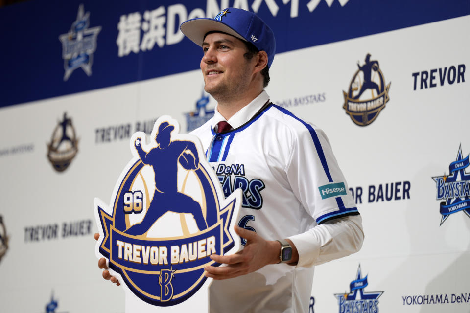 Trevor Bauer with his new uniform and cap of Yokohama DeNA BayStars poses for photographers during a photo session of the news conference Friday, March 24, 2023, in Yokohama, near Tokyo. (AP Photo/Eugene Hoshiko)