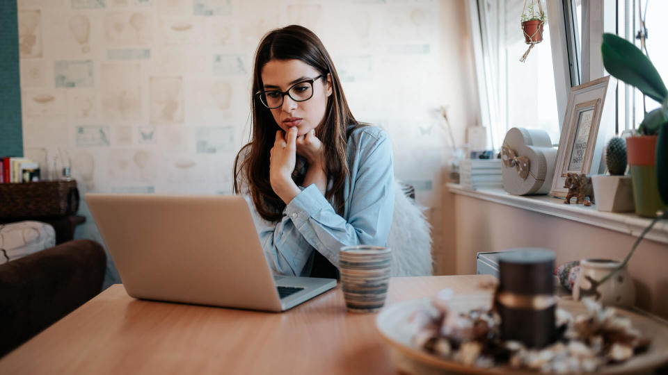 Worried girl looking at laptop screen at home.