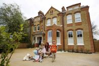 A mother and children place flowers outside a house where the bodies of three children were found, in New Malden, southwest London April 23, 2014. A 43-year-old woman has been arrested on suspicion on murder after the bodies of three children were found at a house in southwest London, police said on Wednesday. Police said a four-year-old girl and two boys, both aged three, were found dead at a residential address in New Malden on Tuesday evening. REUTERS/Olivia Harris (BRITAIN - Tags: CRIME LAW SOCIETY)