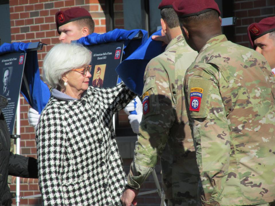 Charlotte Provenza  reveals a photo of her late father, Capt. Charles L. Sartain Jr., as he was inducted into the 82nd Airborne Division's Hall of Fame during a Nov. 19, 2021, ceremony at Fort Bragg. Also shown are the division's command team, Maj. Gen. Christopher Donahue and Command Sgt. Maj. David Pitt.