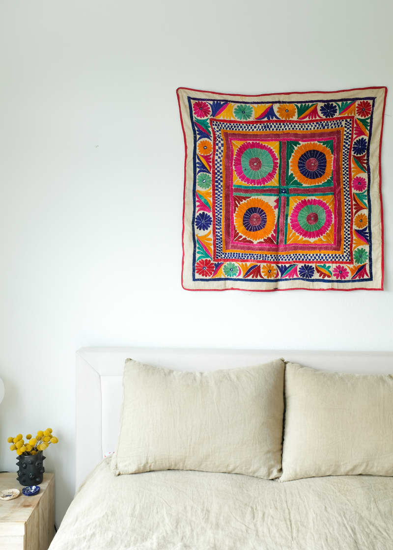 Colorful tapestry hung above bed.