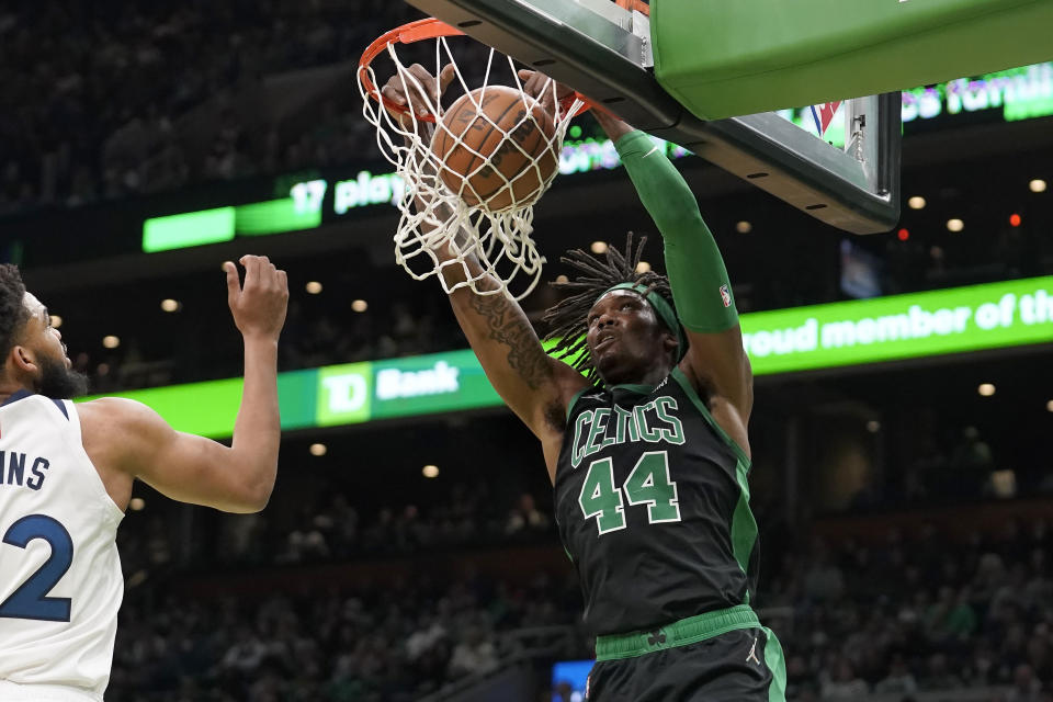 Boston Celtics center Robert Williams III (44) sinks the ball as Minnesota Timberwolves center Karl-Anthony Towns (32), left, tries to defend in the first half of an NBA basketball game, Sunday, March 27, 2022, in Boston. (AP Photo/Steven Senne)