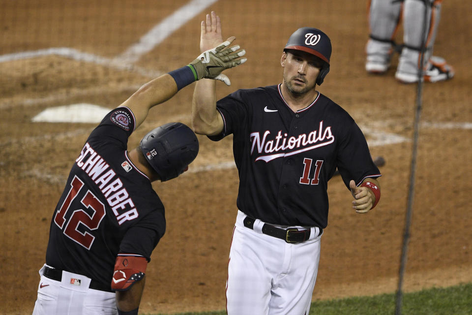 Washington Nationals' Ryan Zimmerman (11) is greeted by teammate Kyle Schwarber (12) after scoring on a single by Josh Bell during the eighth inning of a baseball game against the Baltimore Orioles, Friday, May 21, 2021, in Washington. (AP Photo/Nick Wass)