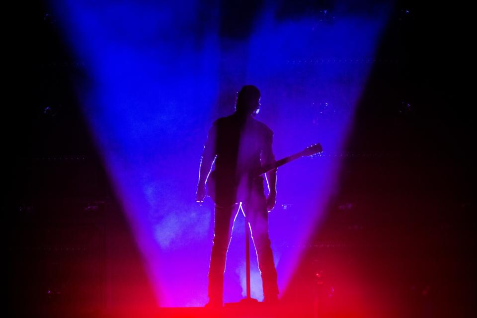 A blue light surrounds Thomas Rhett as he stands onstage