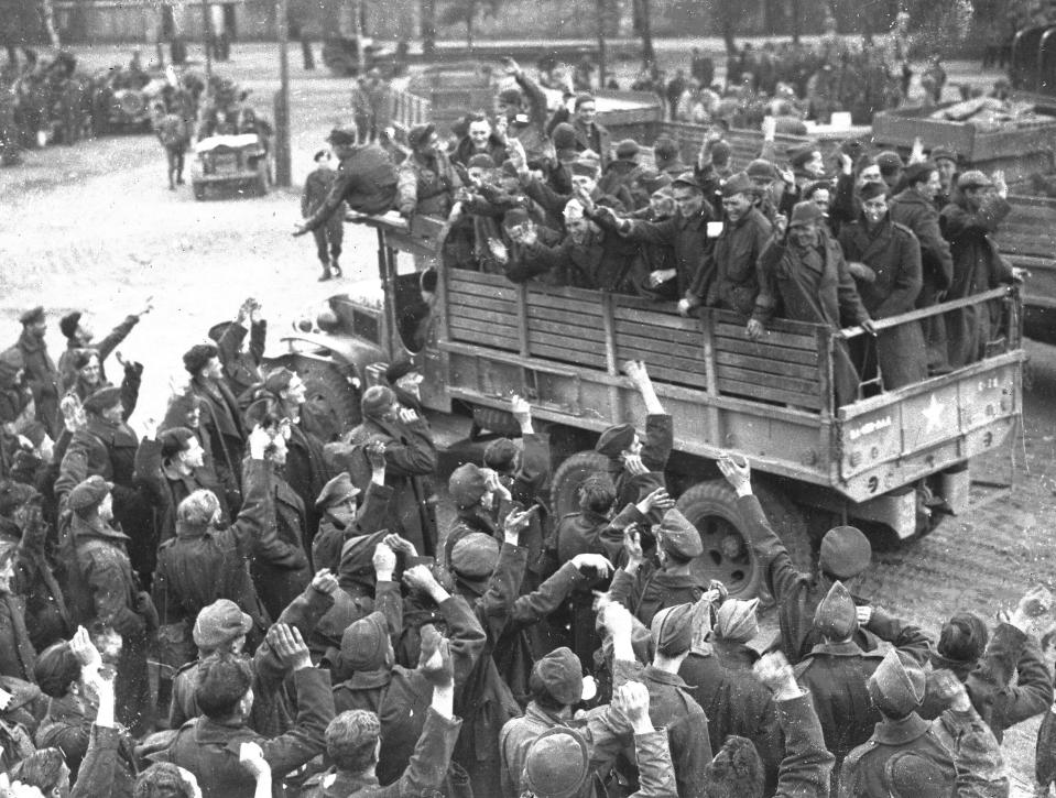 FILE - in this May 7, 1945 file photo British prisoners of war, foreground, bid farewell to fellow prisoners of war, a group of U.S. GIs, as the first U.S. truck leaves for Allied lines, at a camp at Altengrabow, Germany. About 19,000 Allied prisoners will be collected from the camp after consultations between U.S. and German officers revealed the captors could not sustain feeding the prisoners. (AP Photo/Henry L. Griffin, File)