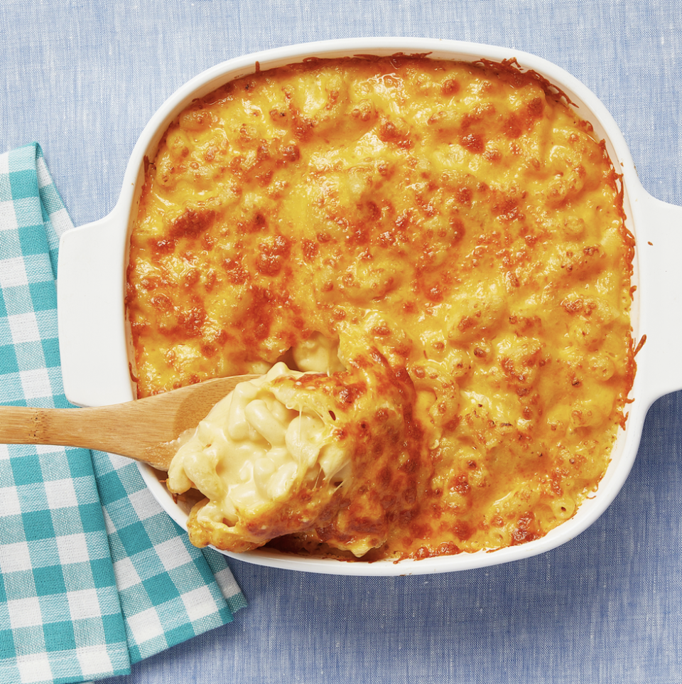macaroni and cheese in white baking dish with wooden spoon