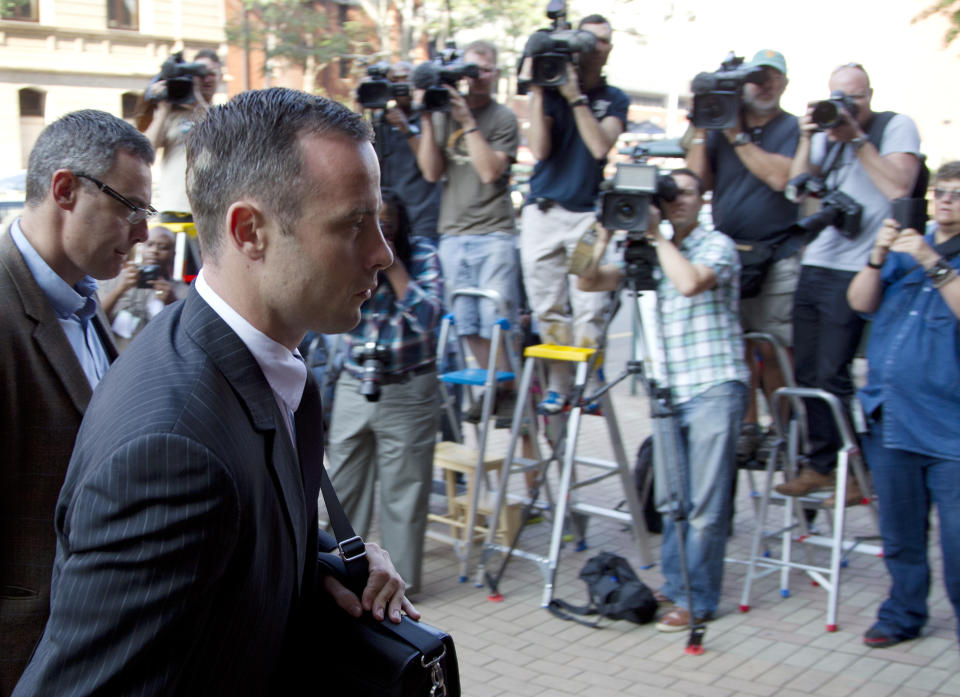 Oscar Pistorius, right accompanied by relative, arrives at the high court in Pretoria, South Africa, Tuesday, March 18, 2014. Pistorius is charged with murder for the shooting death of his girlfriend, Reeva Steenkamp, on Valentines Day in 2013. (AP Photo/Themba Hadebe)