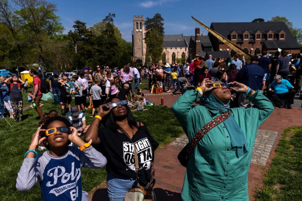 From left, Amir Foushee, 12, Chandra Dunston and Paris Miller-Foushee wear protective glasses while viewing the solar eclipse during a watch party at the Morehead Planetarium and Science Center at UNC-Chapel Hill on Monday, April 8, 2024. Travis Long/tlong@newsobserver.com