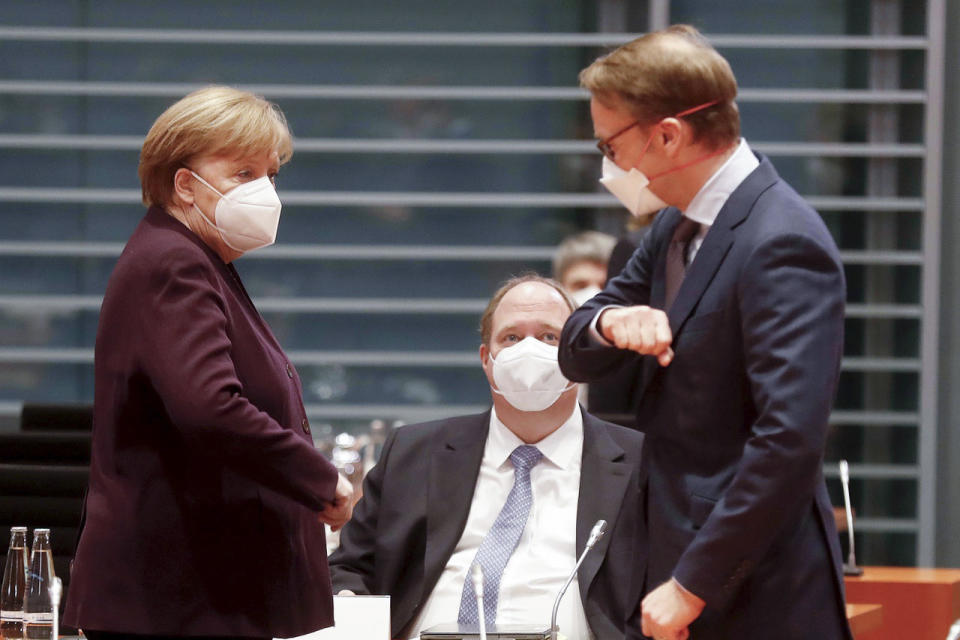 German Chancellor Angela Merkel, left, and Jens Weidmann, right, President of the German Central Bank, greet each other in front of Helge Braun, center, Head of the Federal Chancellery and Federal Minister for Special Tasks, at the beginning of the weekly cabinet meeting at the Chancellery in Berlin, Germany, Wednesday, Jan. 27, 2021. (Sven Darmer/dpa via AP)