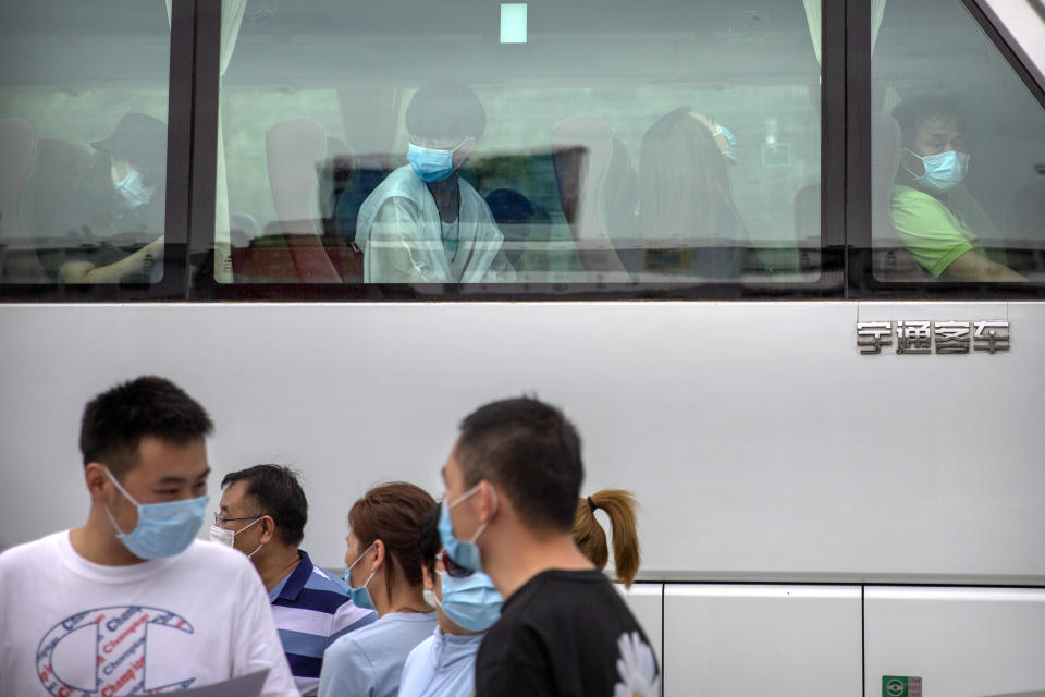People wait to be taken by bus to a COVID-19 testing site after they were ordered by the government to be tested after potentially being exposed to the coronavirus outbreak at a wholesale food market in Beijing, Wednesday, June 17, 2020. As the number of cases of COVID-19 in Beijing climbed in recent days following an outbreak linked to a wholesale food market, officials announced they had identified hundreds of thousands of people who needed to be tested for the coronavirus. (AP Photo/Mark Schiefelbein)