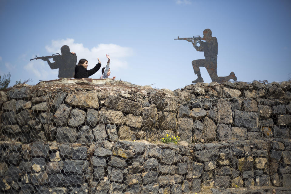 Tourists pose next to a metal cutout of a soldiers in an old outpost in an old military outpost overlooking to Syria in the Israeli controlled Golan Heights, Friday, March 22, 2019. President Donald Trump abruptly declared Thursday the U.S. will recognize Israel's sovereignty over the disputed Golan Heights, a major shift in American policy that gives Israeli Prime Minister Benjamin Netanyahu a political boost a month before what is expected to be a close election.(AP Photo/Ariel Schalit)