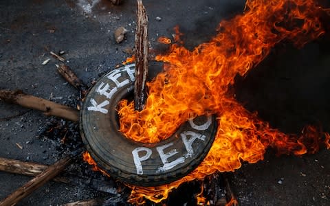 Supporters of the opposition leader Raila Odinga burn a tyre - Credit: EPA