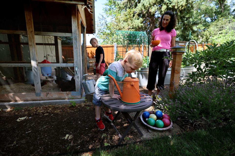 Dr. Bonnie Feola watches as Ellis looks down into a watering can in her garden in Salt Lake City on Wednesday, July 26, 2023. Feola works with kids and parents on learning about eating healthy and how to prepare food. | Scott G Winterton, Deseret News