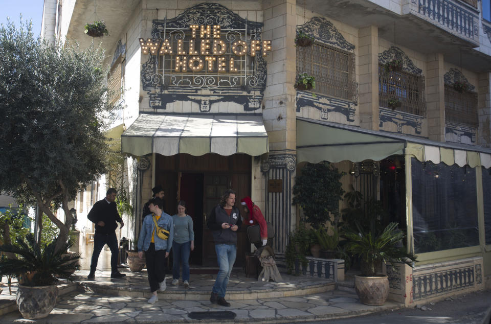 Visitors leave the Walled Off Hotel, where a new artwork dubbed "Scar of Bethlehem" by the artist Banksy is displayed, in the West Bank city of Bethlehem, Sunday, Dec. 22, 2019. (AP Photo/Majdi Mohammed)