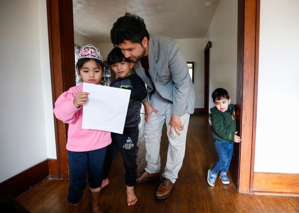 Six-year-old Behishta shows her dad Romal Noori and brother Abdul Bais, also 6, a drawing she made at their home on Saturday, Dec. 17, 2022.