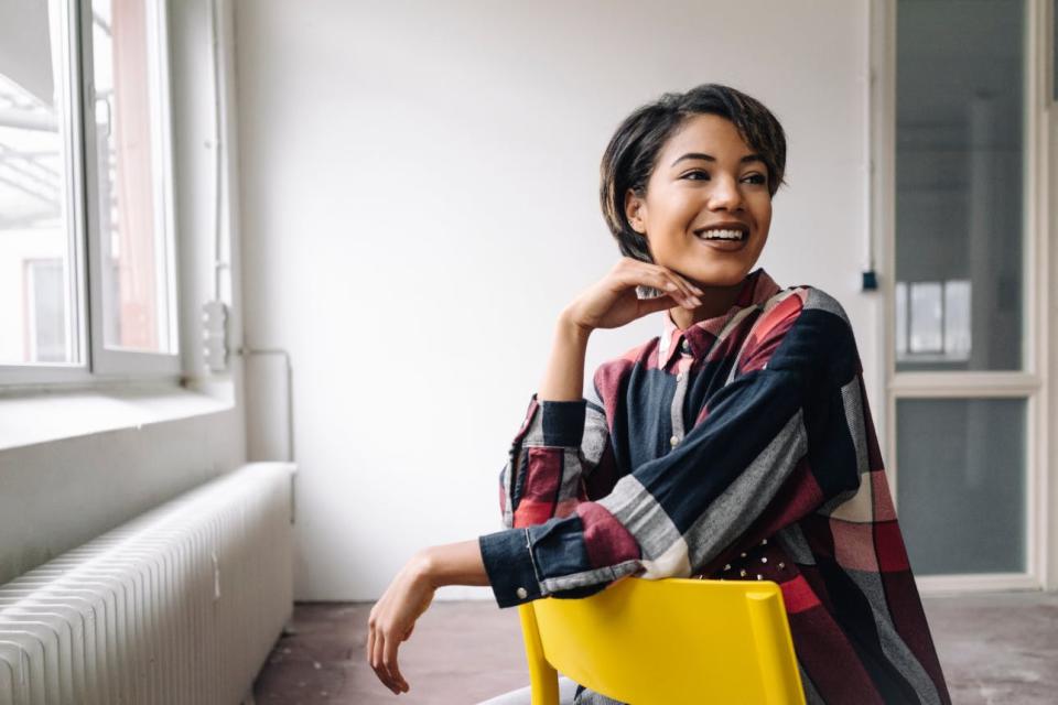 A smiling woman sits in a backwards-facing chair