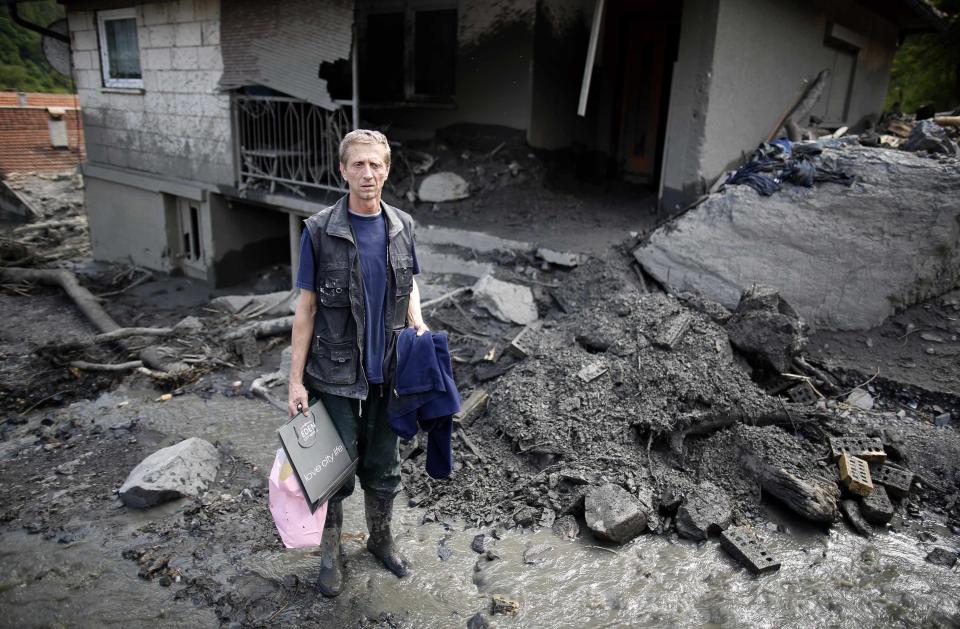 Amir Kozlic, poses in front of his flood-damaged house in Topcic Polje