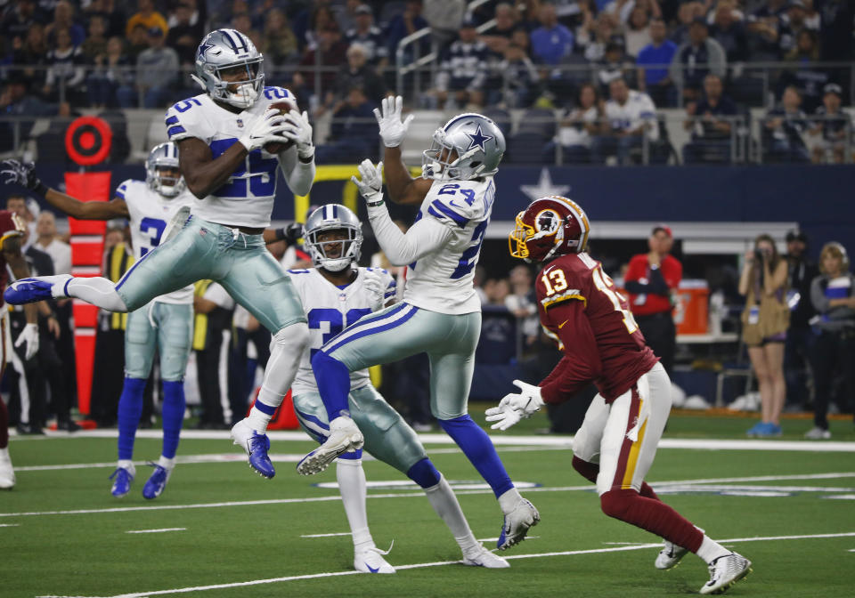 Dallas Cowboys free safety Xavier Woods (25) intercepts a pass next to cornerback Chidobe Awuzie (24) and Washington Redskins wide receiver Maurice Harris (13) during the second half of an NFL football game in Arlington, Texas, Thursday, Nov. 22, 2018. (AP Photo/Michael Ainsworth)