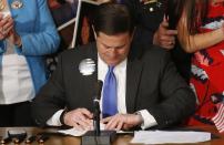 Arizona Republican Gov. Doug Ducey signs into law a distracted driving bill at a signing ceremony at the Arizona Capitol Monday, April 22, 2019, in Phoenix. Arizona becomes the 48th state to ban texting and the 18th to ban any hand-held phone use while driving. Officers can begin issuing warnings immediately and can write tickets in 2021. (AP Photo/Ross D. Franklin)