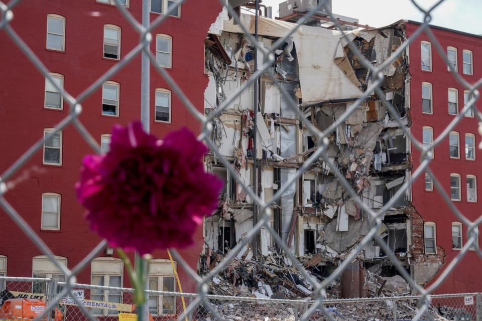 A flower hangs from a fence at the where on Sunday an apartment building partially collapsed in Davenport, Iow (Copyright 2023 The Associated Press. All rights reserved.)