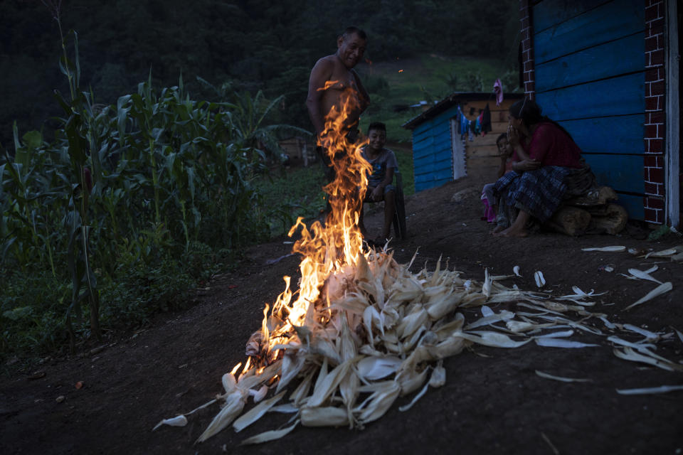 Residents burn discarded corn husks in the makeshift settlement Nuevo Queja, Guatemala, Friday, July 9, 2021. Residents of the settlement were left destitute in November 2020 when a mudslide triggered by Hurricane Eta buried their Guatemalan town. (AP Photo/Rodrigo Abd)
