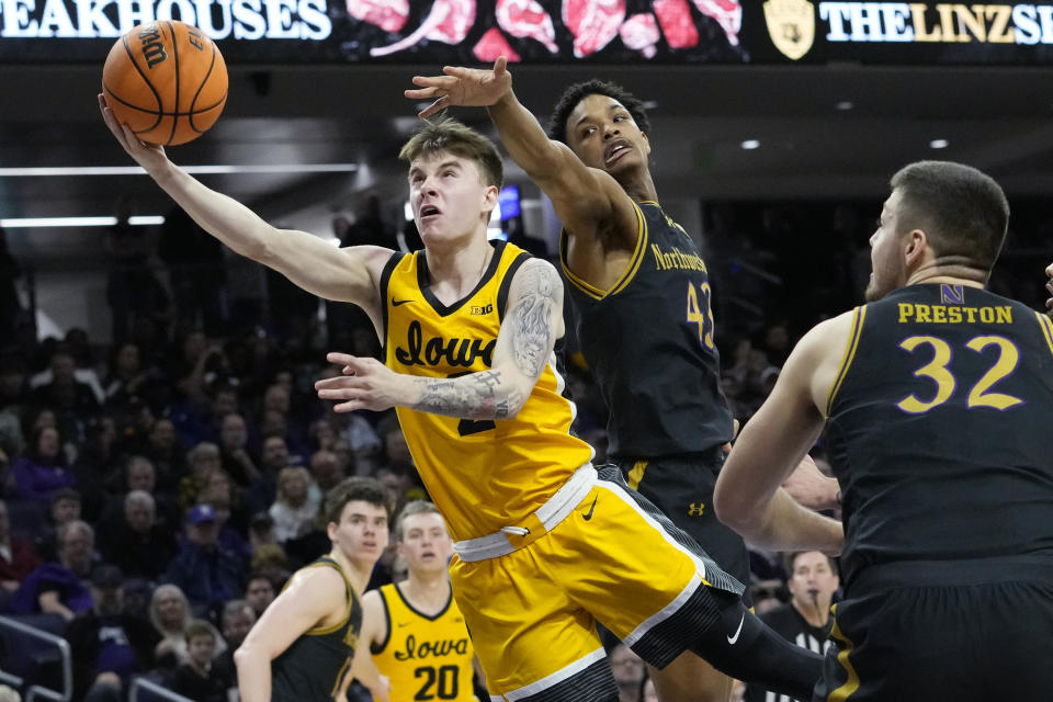 Iowa guard Brock Harding, left, drives to the basket past Northwestern guard Blake Smith during the first half of an NCAA college basketball game in Evanston, Ill., Saturday, March 2, 2024. (AP Photo/Nam Y. Huh)