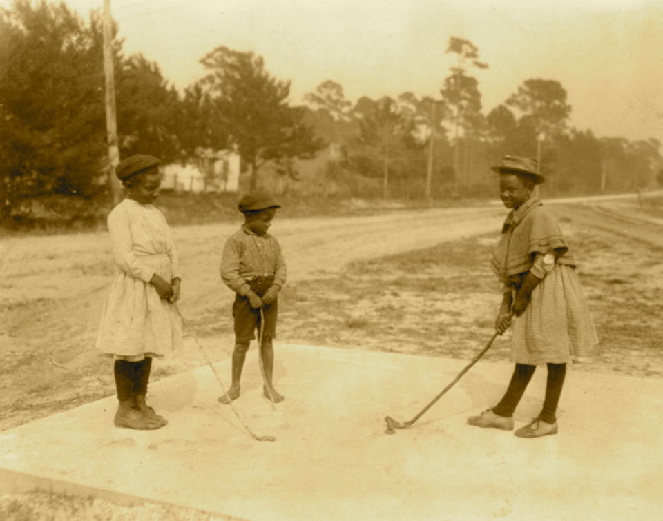 Circa 1905:  Three children playing golf with clubs made of sticks.  (Photo by Buyenlarge/Getty Images)