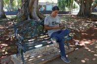 Alex Sobrino, founder of the Telegram channel CubaCripto, checks market trades of bitcoins at a park in Havana