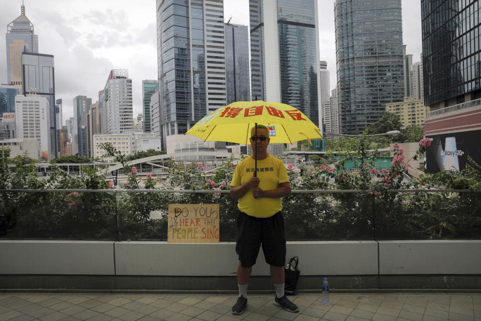 A man holds an umbrella outside the Legislative Council following last weekend's massive protest against the unpopular extradition bill in Hong Kong, Tuesday, June 18, 2019. Hong Kong's government headquarters reopened Tuesday as the number of protesters outside dwindled to a few dozen and life returned to normal in the former British colony. (AP Photo/Vincent Yu)