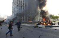 People run to help a wounded man as smoke rises from the site of an explosion in Beirut's downtown area December 27, 2013. Former Lebanese minister Mohammed Shattah, who opposed Syrian President Bashar al-Assad, was killed in an explosion that targeted his convoy in Beirut on Friday along with at least four other people, security sources said. REUTERS/Jamal Saidi