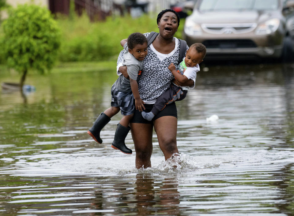 Terrian Jones reacts as she feels something moving in the water at her feet as she carries Drew and Chance Furlough to their mother on Belfast Street in New Orleans during flooding earlier this week.&nbsp; (Photo: ASSOCIATED PRESS)