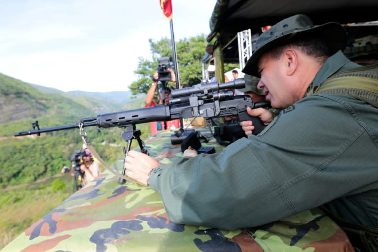 In this handout picture released by the Venezuelan presidency, Defense Minister General Vladimir Padrino aims a rifle during military drills