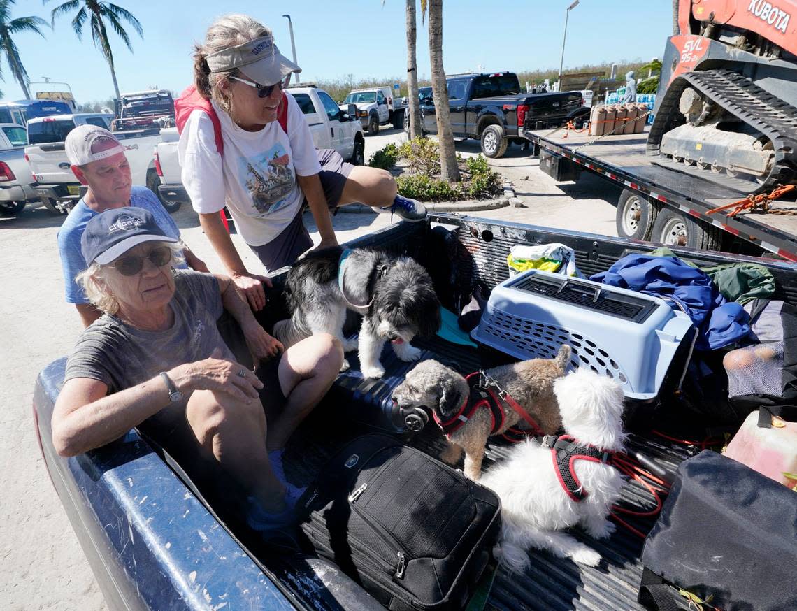 Steve Gibson, left background, helps Maria Zoltac into the back of his truck as her sister Susan, Zoltac, left, makes herself comfortable with her dogs after being rescued from Sanibel Island Saturday, Oct. 1, 2022, in Fort Myers, Fla. (AP Photo/Steve Helber)