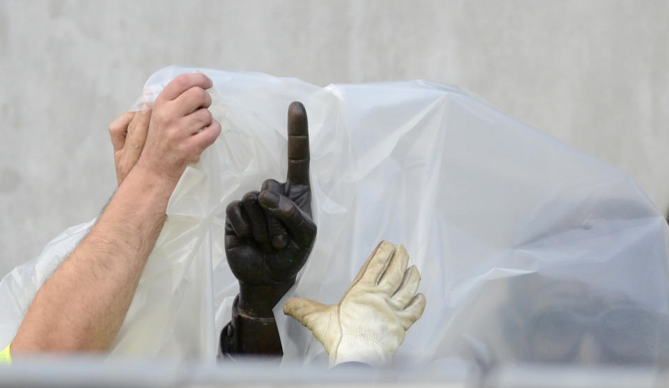 Workers handle the statue of former Penn State football coach Joe Paterno before removing the statue Sunday, July 22, 2012, in State College, Pa. The famed statue of Paterno was taken down from outside the Penn State football stadium Sunday, eliminating a key piece of the iconography surrounding the once-sainted football coach accused of burying child sex abuse allegations against a retired assistant.  (AP Photo/John Beale)