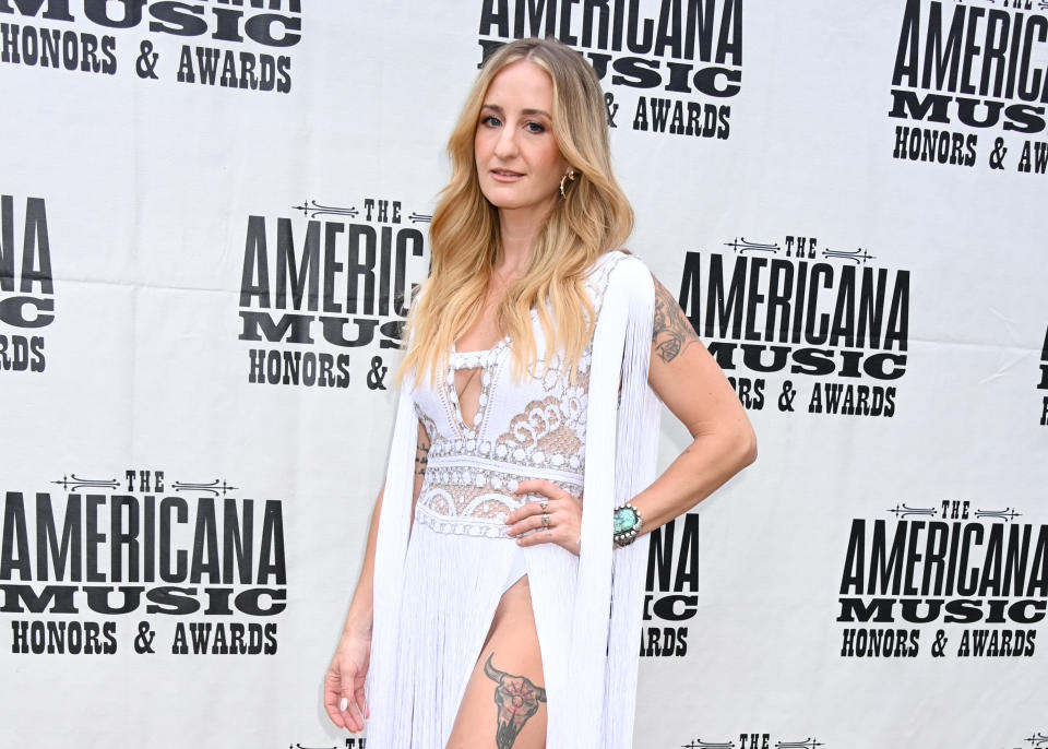 Woman in a white lace dress stands at the Americana Music Honors & Awards event