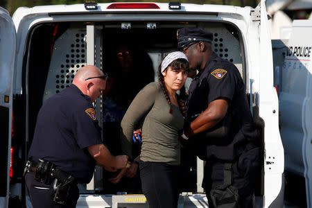 A female activist is handcuffed with others after raising a banner from the flag poles outside the Rock and Roll Hall of Fame during the Republican National Convention in Cleveland. REUTERS/Adrees Latif