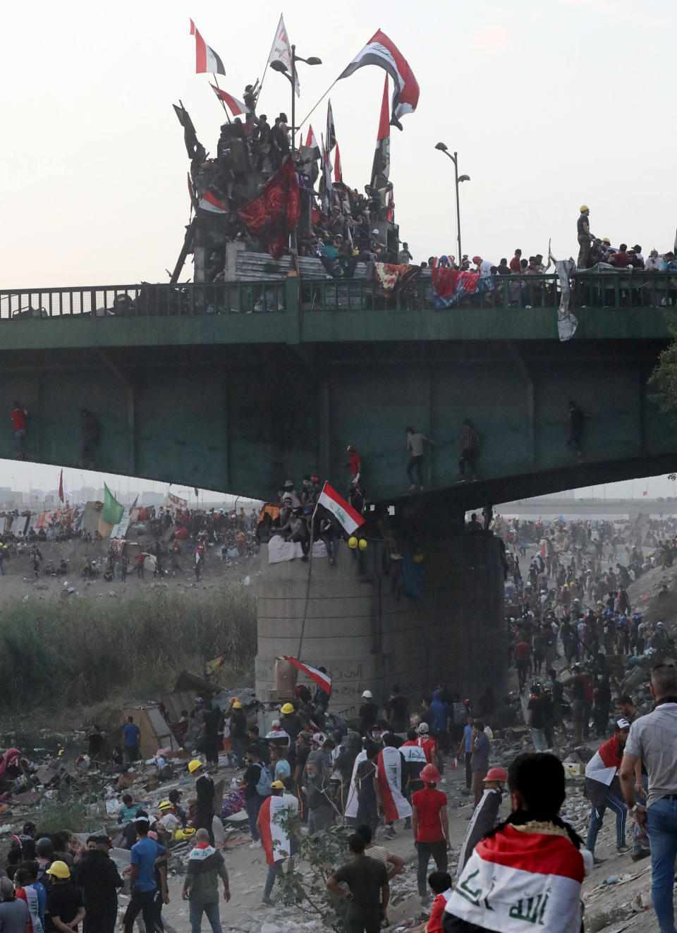 Anti-government protesters stand on barriers set by Iraqi security forces and gather around the Joumhouriya bridge leading to the Green Zone government areas during ongoing protests in Baghdad, Iraq, Sunday, Nov. 3, 2019. (AP Photo/Khalid Mohammed)